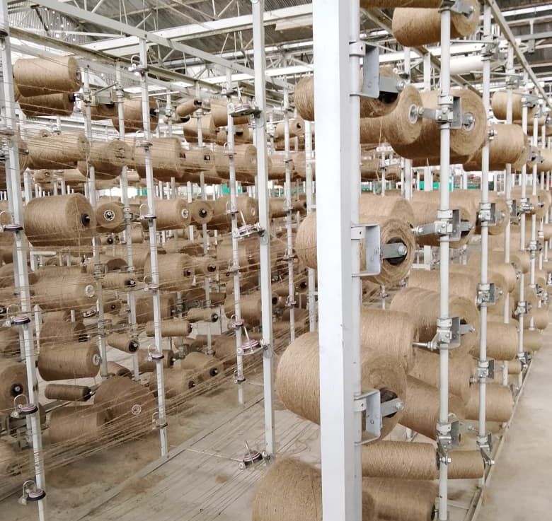 Creel racks loaded with jute yarn cops feeding the weaving preparation area